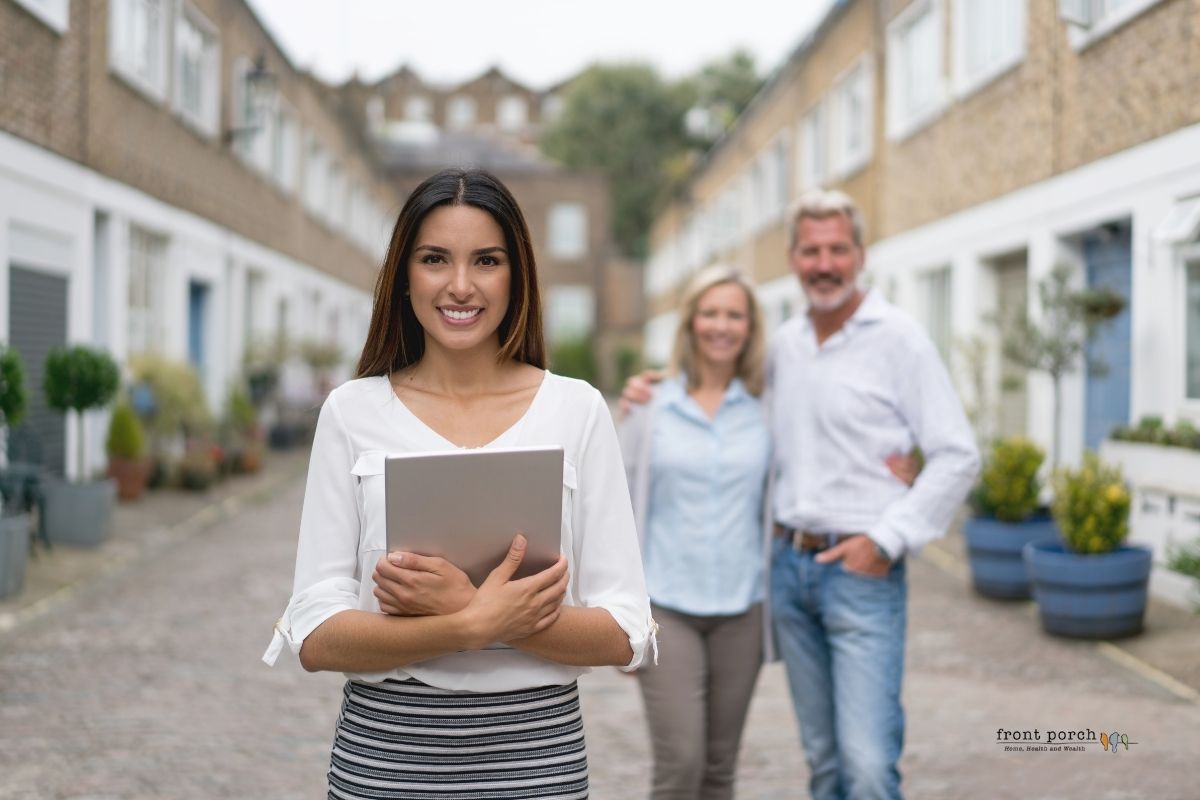 real estate agent standing with sellers in a neighborhood