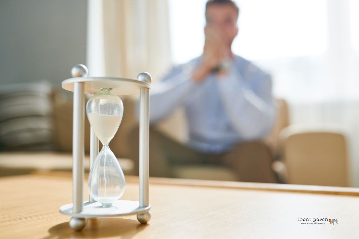 man sitting on a sofa staring at a hour glass waiting to buy
